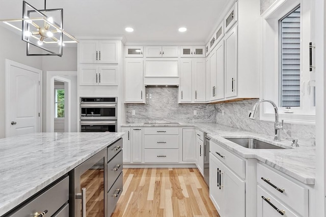 kitchen with appliances with stainless steel finishes, white cabinetry, wine cooler, sink, and hanging light fixtures