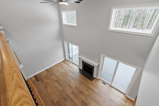 unfurnished living room featuring light hardwood / wood-style flooring, a high ceiling, and ceiling fan