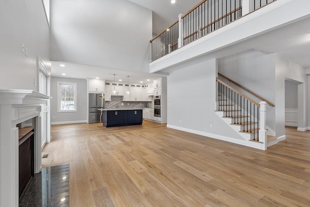 unfurnished living room featuring light hardwood / wood-style floors and a high ceiling