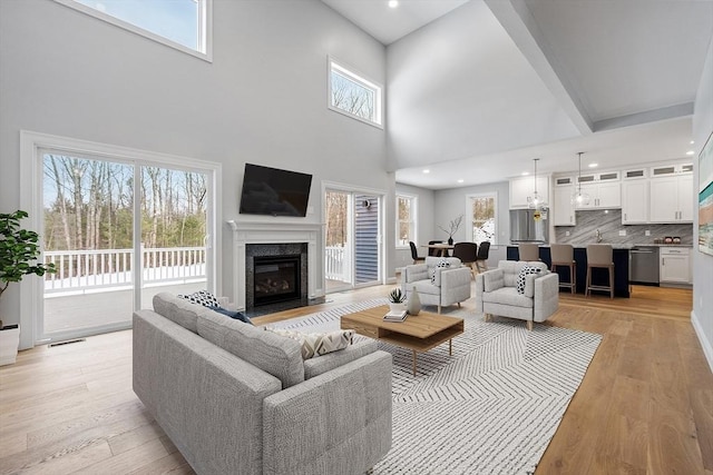 living room with a high ceiling, light hardwood / wood-style floors, and a fireplace