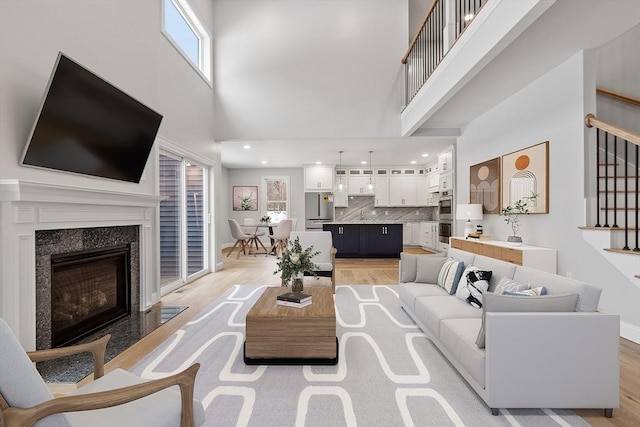 living room with light hardwood / wood-style floors, a high ceiling, and a high end fireplace