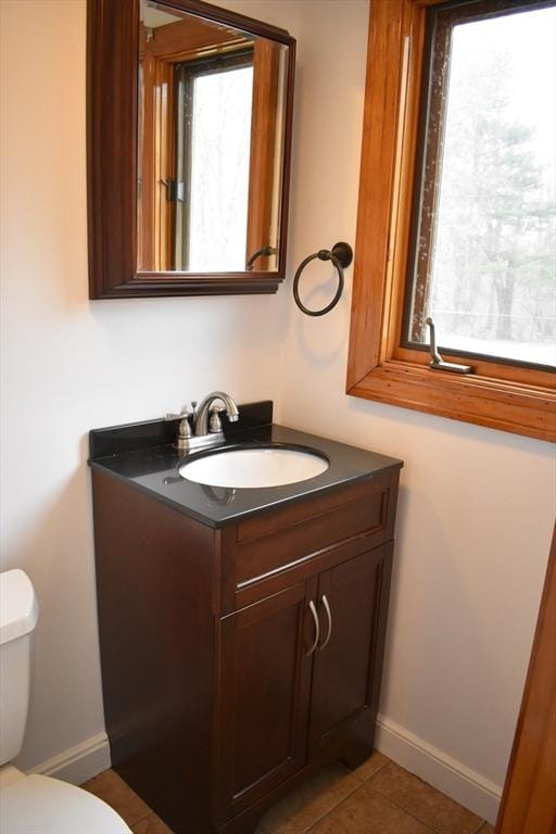 bathroom with tile patterned floors, vanity, toilet, and a wealth of natural light