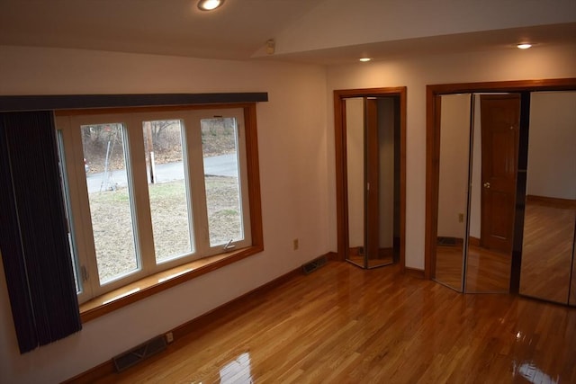 unfurnished bedroom featuring hardwood / wood-style floors and lofted ceiling