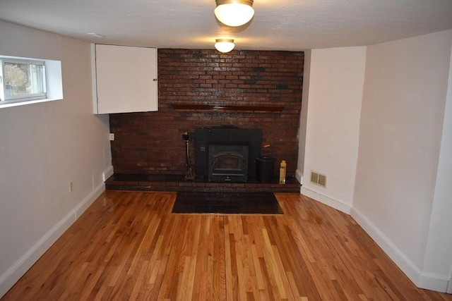 unfurnished living room featuring light wood-type flooring and a wood stove