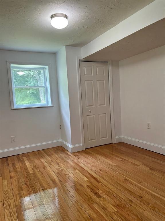 unfurnished bedroom with a closet, light hardwood / wood-style flooring, and a textured ceiling