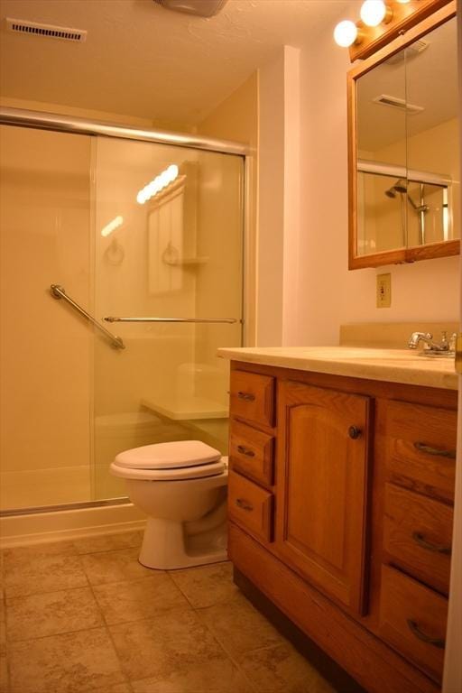 bathroom with tile patterned flooring, vanity, an enclosed shower, and toilet