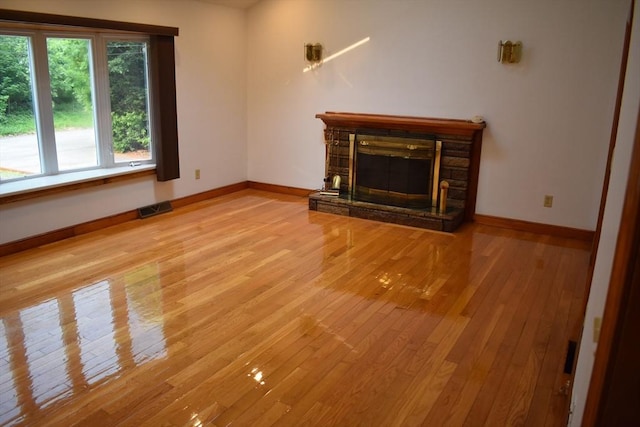 unfurnished living room featuring light hardwood / wood-style flooring and a stone fireplace