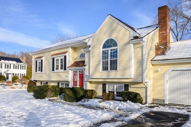 split foyer home featuring a garage and a chimney