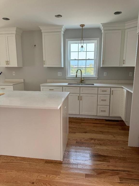 kitchen with hardwood / wood-style flooring, pendant lighting, sink, and white cabinets