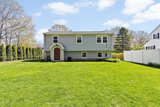 back of property with a yard and fence