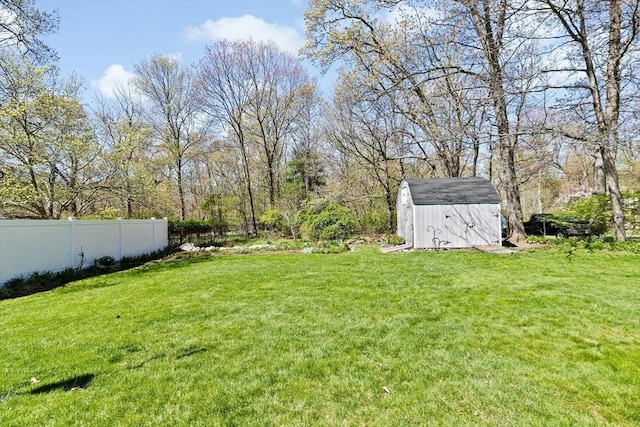 view of yard with an outdoor structure, fence, and a storage shed