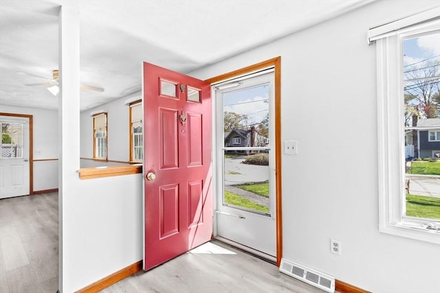 foyer entrance featuring baseboards, visible vents, a healthy amount of sunlight, and wood finished floors
