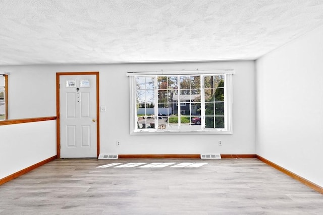 spare room with a textured ceiling, visible vents, and wood finished floors