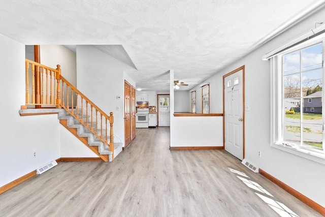 unfurnished living room featuring visible vents, baseboards, and wood finished floors
