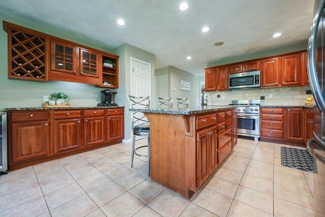 70 Huntsbridge Rd, North Attleboro, MA 02760 - kitchen with appliances with stainless steel finishes, a kitchen breakfast bar, dark stone counters, recessed lighting, and tasteful backsplash