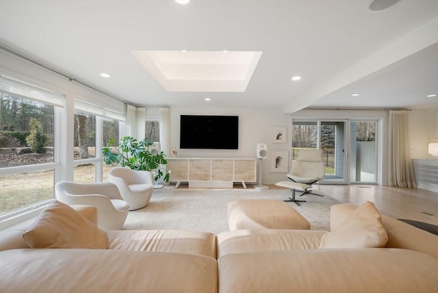 living area with recessed lighting, a raised ceiling, and a skylight