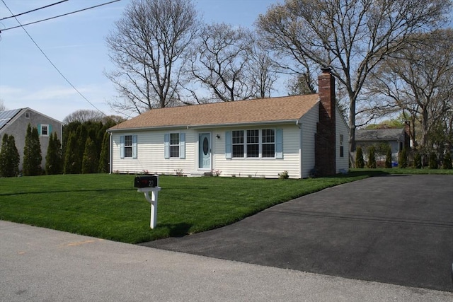 view of front of home with a chimney, driveway, and a front lawn