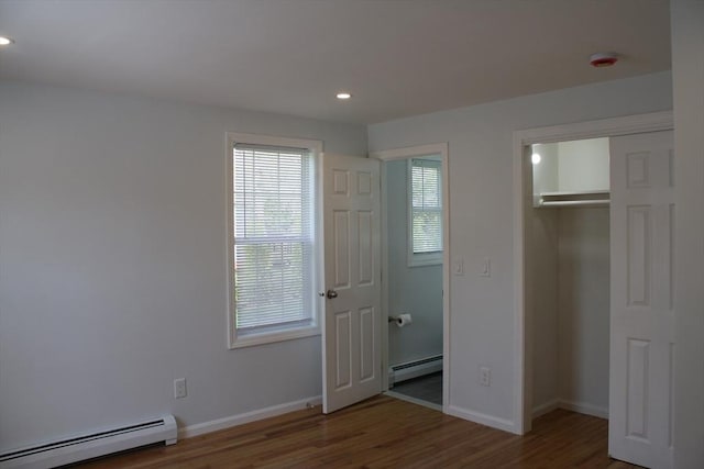 unfurnished bedroom featuring recessed lighting, a baseboard heating unit, and wood finished floors
