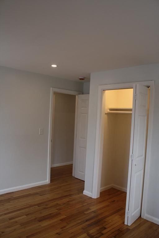 unfurnished bedroom featuring recessed lighting, baseboards, wood finished floors, and a closet