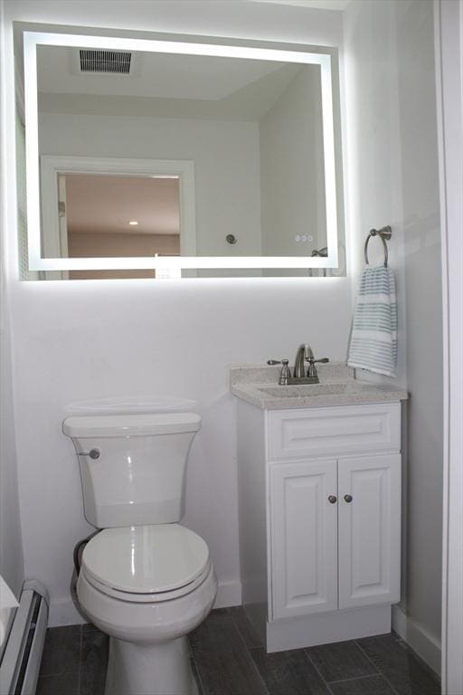 half bath featuring baseboards, a baseboard radiator, vanity, and visible vents