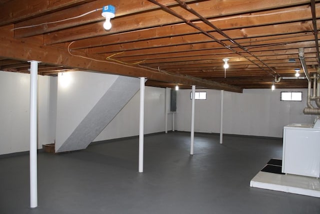 basement featuring plenty of natural light, electric panel, and washer / clothes dryer