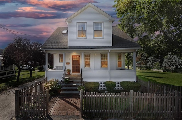 view of front facade with a porch, a shingled roof, and a fenced front yard