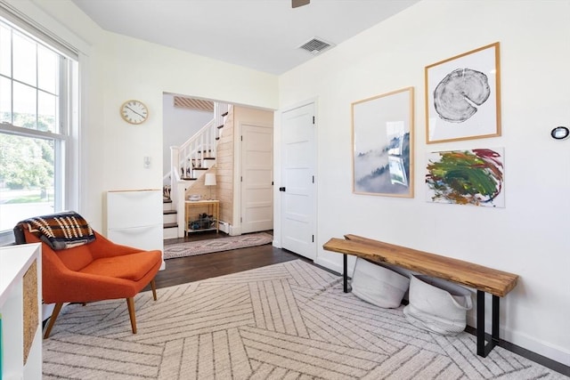 living area featuring stairs, baseboards, visible vents, and wood finished floors