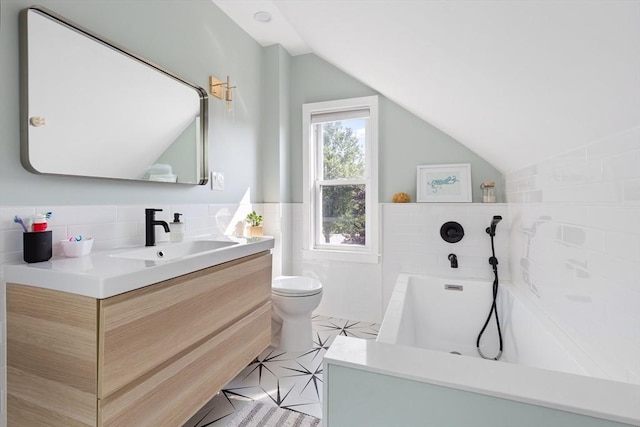 bathroom with a tub, tile walls, vaulted ceiling, vanity, and toilet