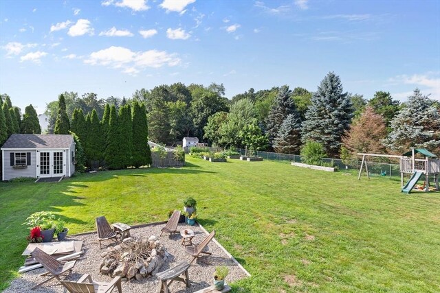 view of yard with fence private yard, french doors, a playground, an outdoor fire pit, and an outbuilding