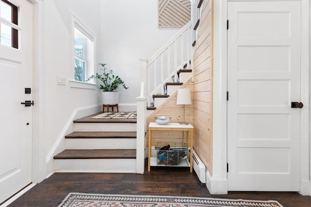 stairs with a baseboard heating unit and wood finished floors