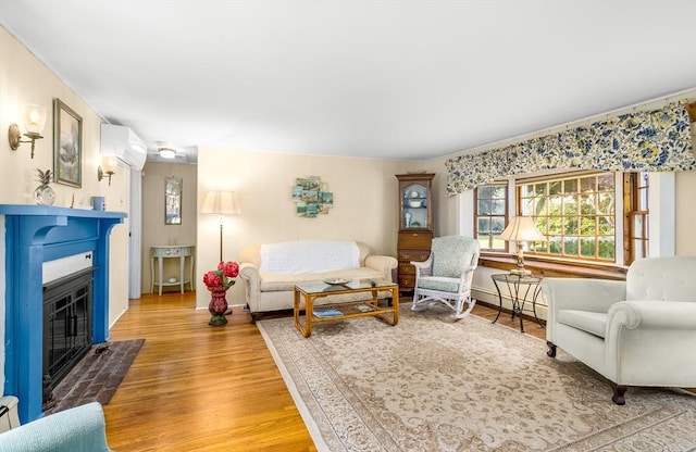 68 Fifth Ave, Barnstable, MA 02601 - living room featuring an AC wall unit, a fireplace with flush hearth, light wood-style flooring, and a baseboard heating unit