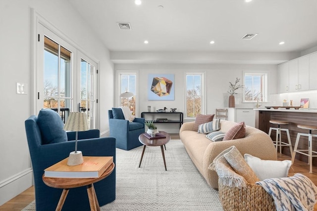 living room with baseboards, visible vents, light wood-style floors, and recessed lighting