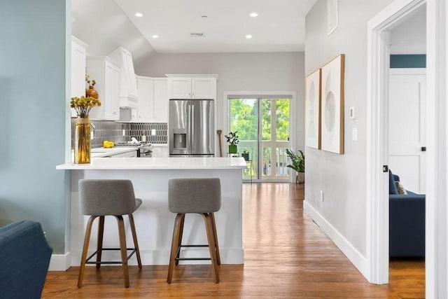 34 Alpha Rd Unit 3, Boston, MA 02124 - kitchen with stainless steel fridge, a peninsula, a breakfast bar area, decorative backsplash, and light countertops