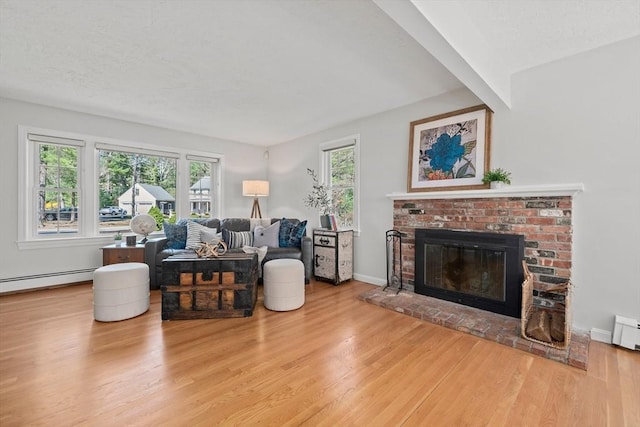 living area with a baseboard heating unit, baseboards, wood finished floors, and a fireplace