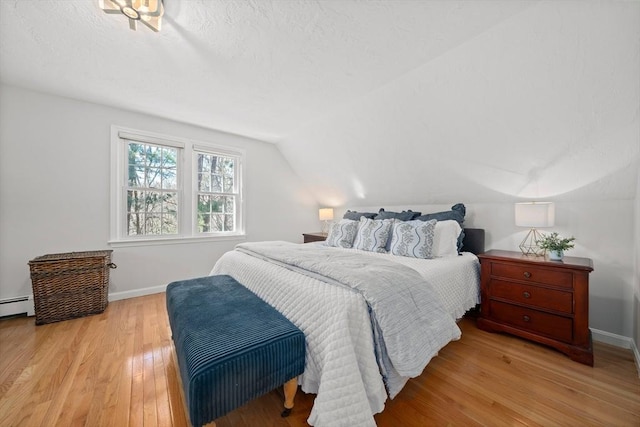 bedroom featuring lofted ceiling, baseboards, wood finished floors, and a textured ceiling