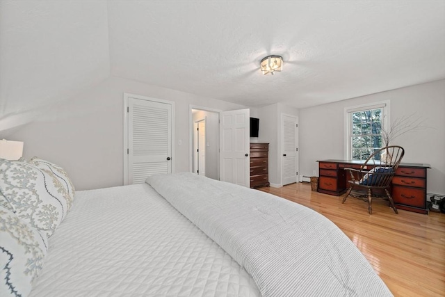 bedroom with light wood finished floors and a baseboard heating unit