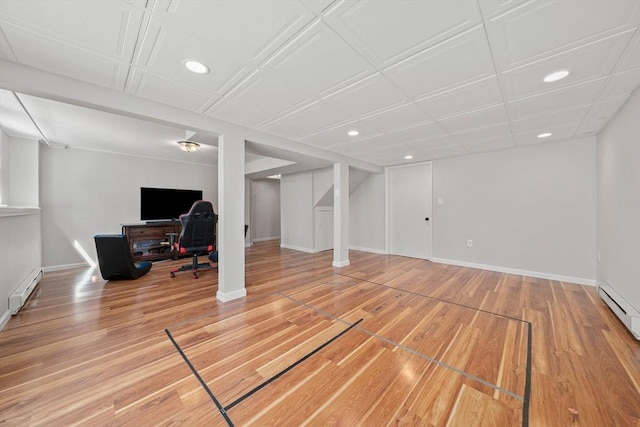 finished basement featuring a baseboard heating unit, light wood-style flooring, baseboards, and recessed lighting