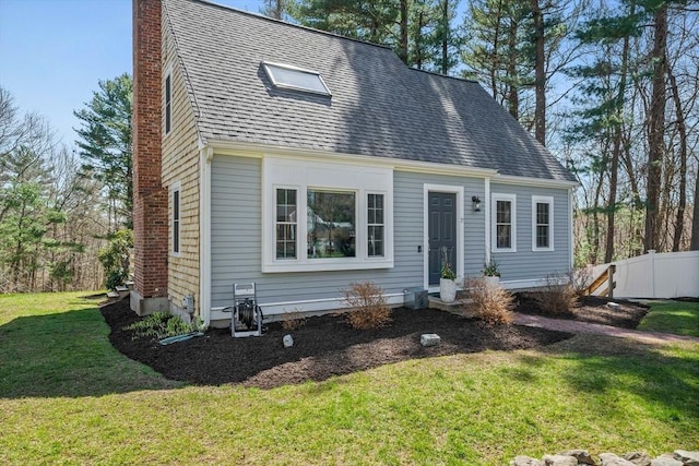 cape cod-style house with fence, a front lawn, roof with shingles, and a chimney