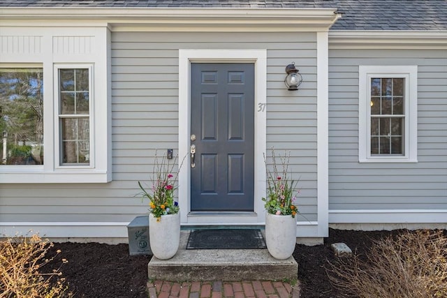 view of exterior entry with a shingled roof