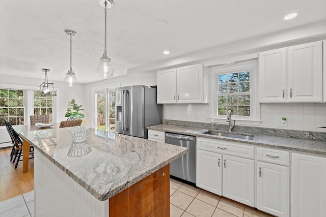 kitchen featuring a wealth of natural light, appliances with stainless steel finishes, a sink, and light tile patterned flooring