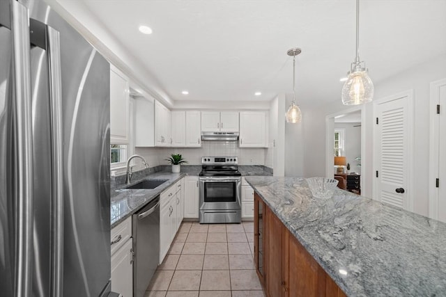 kitchen featuring white cabinets, under cabinet range hood, a sink, and appliances with stainless steel finishes