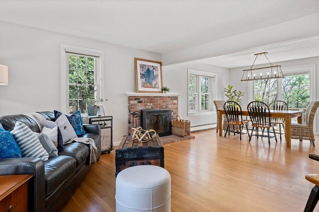 living area with a brick fireplace, wood finished floors, and a baseboard radiator