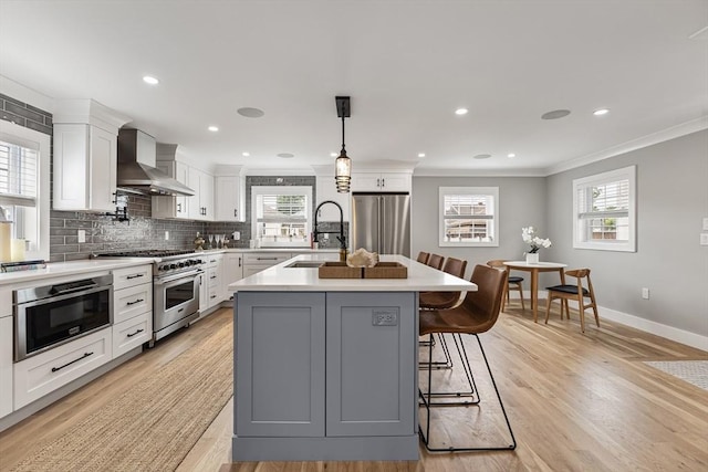 1 Wall St, Quincy, MA 02169 - kitchen featuring wall chimney range hood, high quality appliances, light countertops, decorative backsplash, and white cabinetry