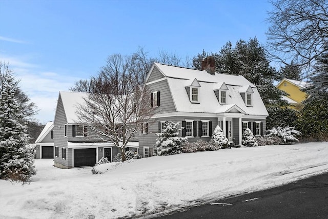 view of front facade with an attached garage, a chimney, and a gambrel roof