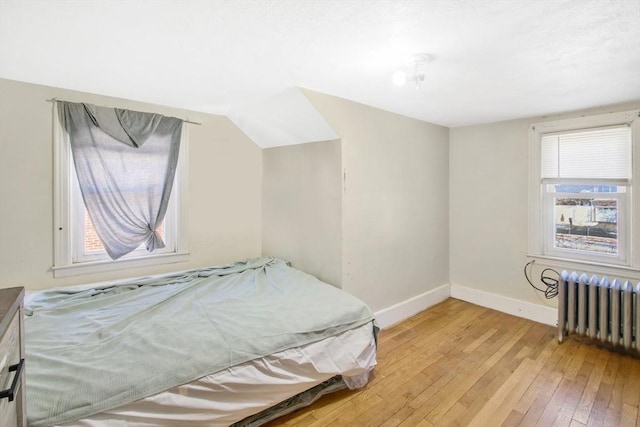 bedroom with radiator heating unit and light hardwood / wood-style floors