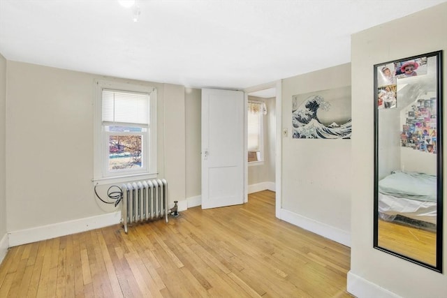 empty room featuring radiator heating unit and light wood-type flooring