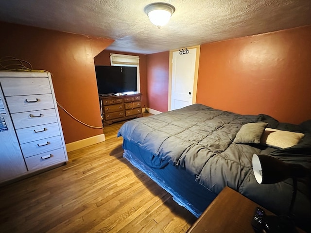 bedroom featuring a textured ceiling and light hardwood / wood-style flooring