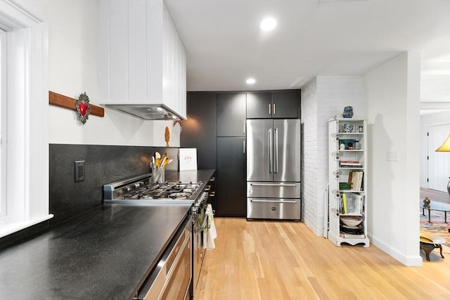 kitchen with high quality appliances, light wood-style flooring, dark countertops, recessed lighting, and baseboards