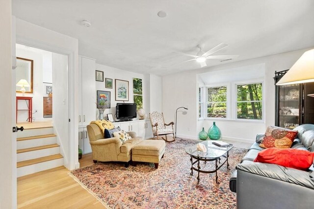 living area with wood finished floors, a ceiling fan, and baseboards