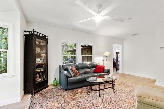living area featuring light wood-style floors, healthy amount of natural light, a ceiling fan, and baseboards
